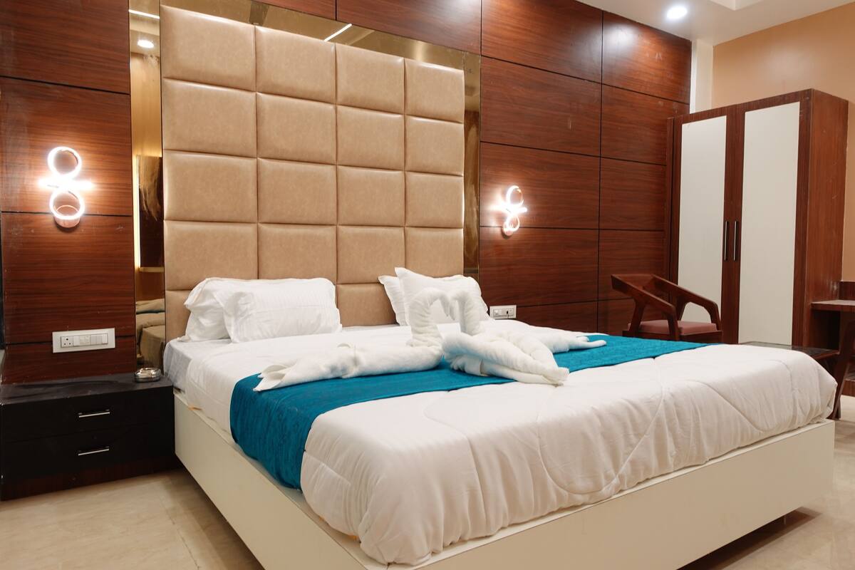 Une chambre d’hôtel moderne avec un grand lit, une tête de lit en bois et une armoire intégrée.