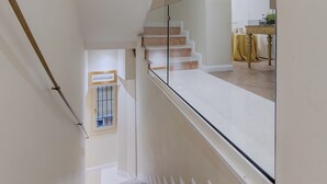 A staircase with white steps and a glass railing, leading to a landing with a table and a yellow tablecloth. - Cà dell'Arte Boutique (Venice)