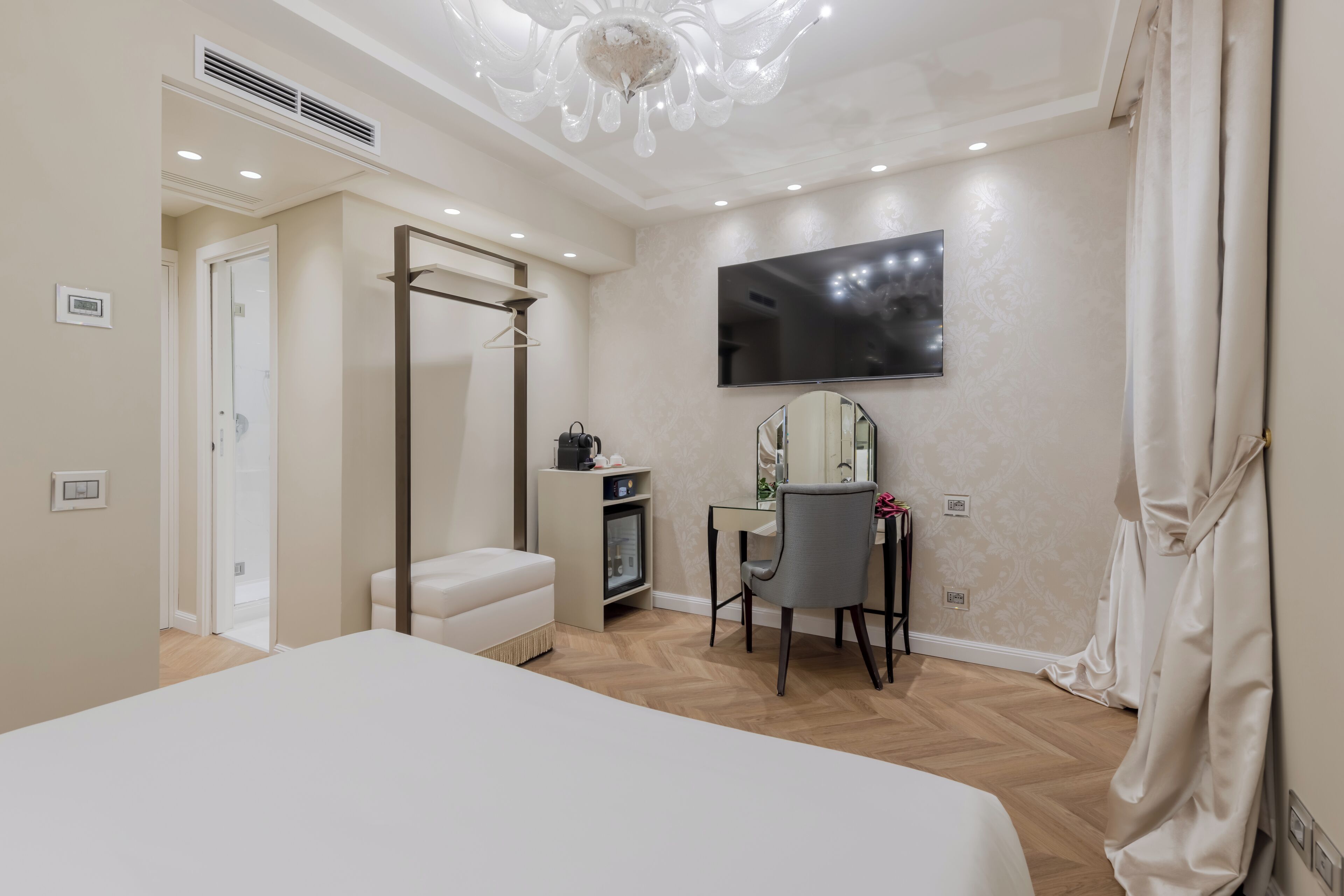 Une chambre moderne avec un grand lit, un bureau avec une chaise, une télévision et une armoire.