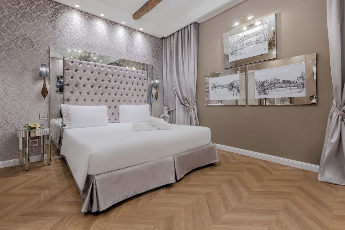 A modern bedroom with a tufted headboard, a large bed, a bedside table, and wall-mounted artwork.