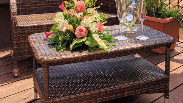Wicker furniture with a table set for two, a bottle of Sol, and a bouquet of flowers. - Cà dell'Arte Boutique (Venice)