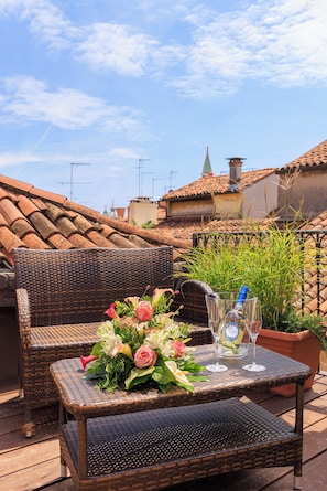 Wicker furniture with a table set for two, a bottle of Sol, and a bouquet of flowers. - Cà dell'Arte Boutique (Venice)