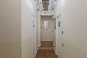 A hallway with a wooden floor, white walls, and a mirror on the wall. - Cà dell'Arte Boutique (Venice)