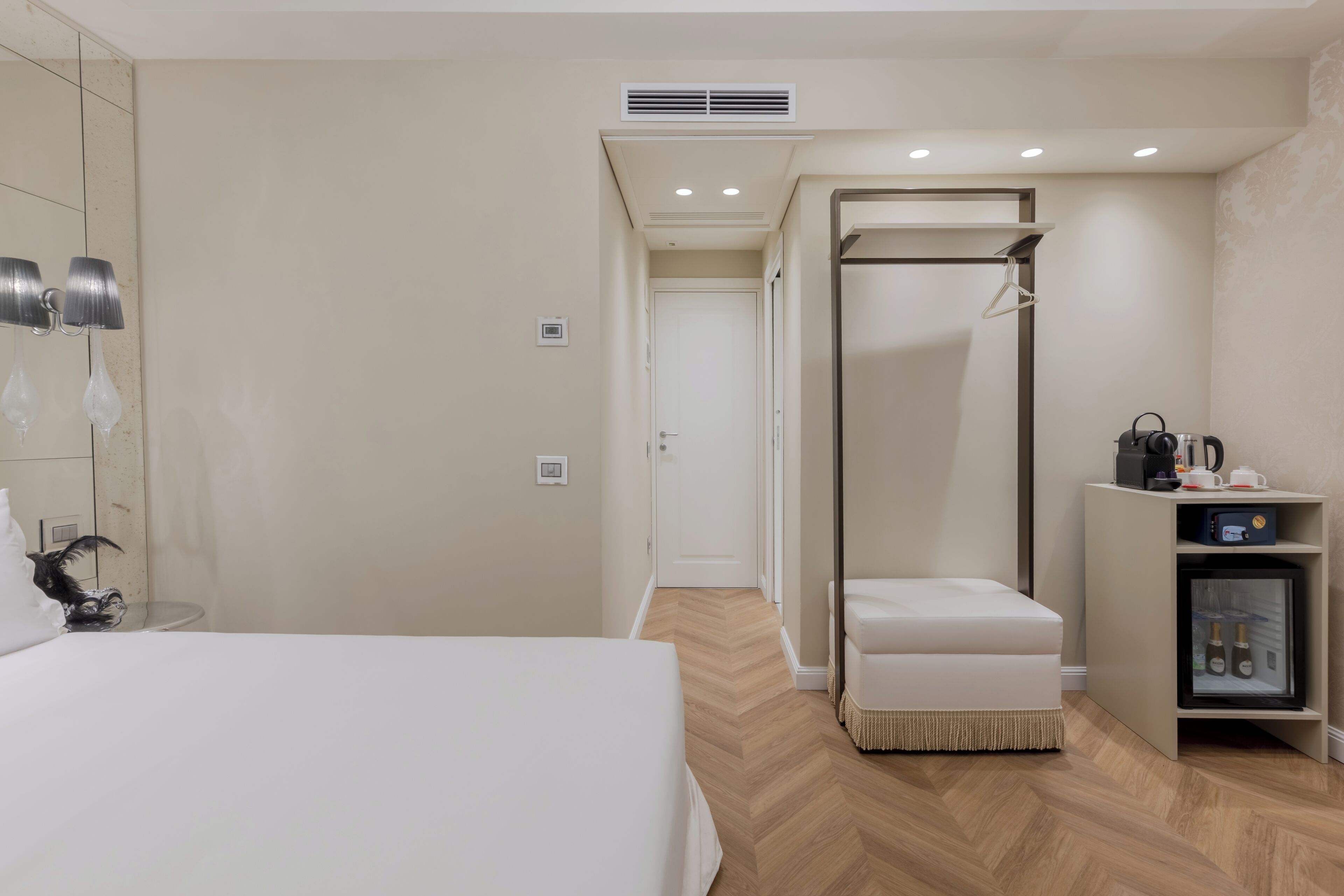 Et hotelværelse med seng, et walk-in closet, minibar og bruseområde.