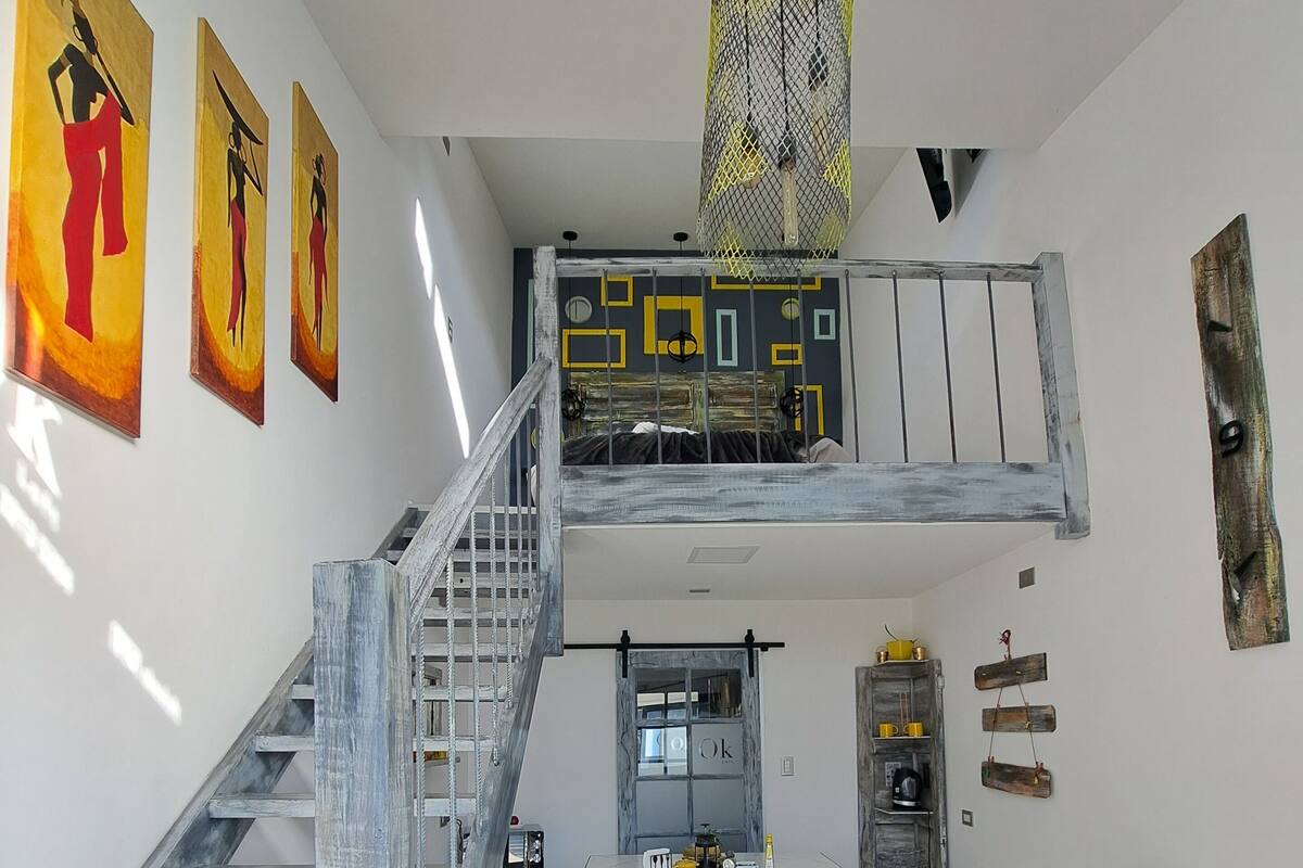 Habitación estilo loft con escalera, comedor y litera.