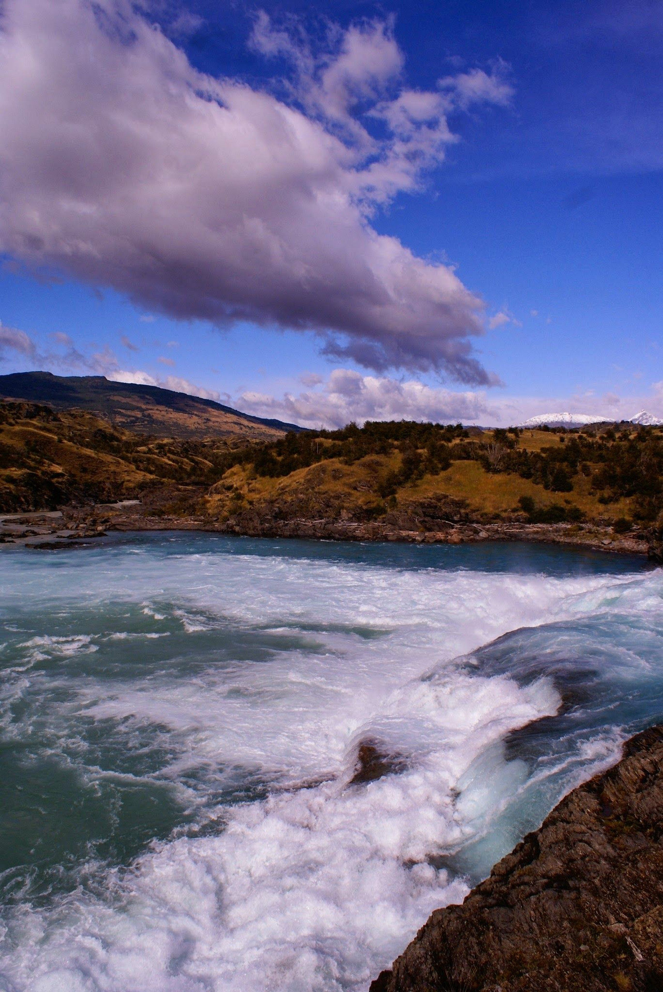 Un río serpentea a través de un paisaje montañoso con terreno rocoso y vegetación escasa.