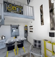 A modern interior with a dining area, a loft space, and a kitchen.