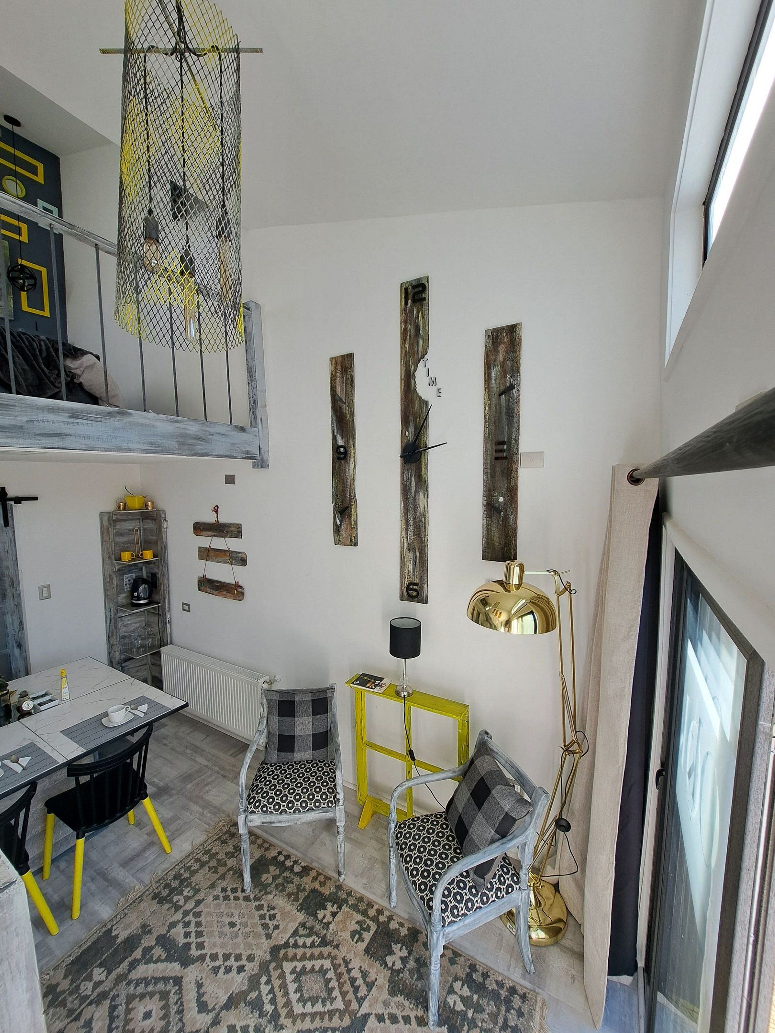 Ein modernes Interieur mit Essbereich, zwei gemusterten Stühlen, einem gelben Beistelltisch, einer Pendelleuchte und einem außergewöhnlichen Deckenleuchter.