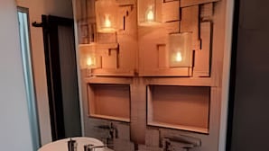 Un baño moderno con dos lavamanos, un espejo y un diseño geométrico en la pared.