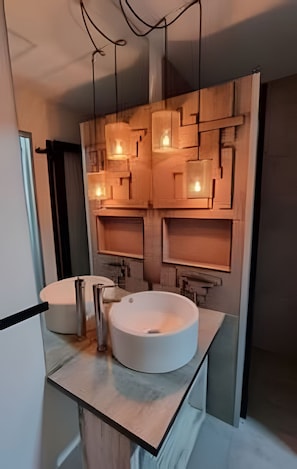 A modern bathroom with two sinks, a mirror, and a geometric wall design.