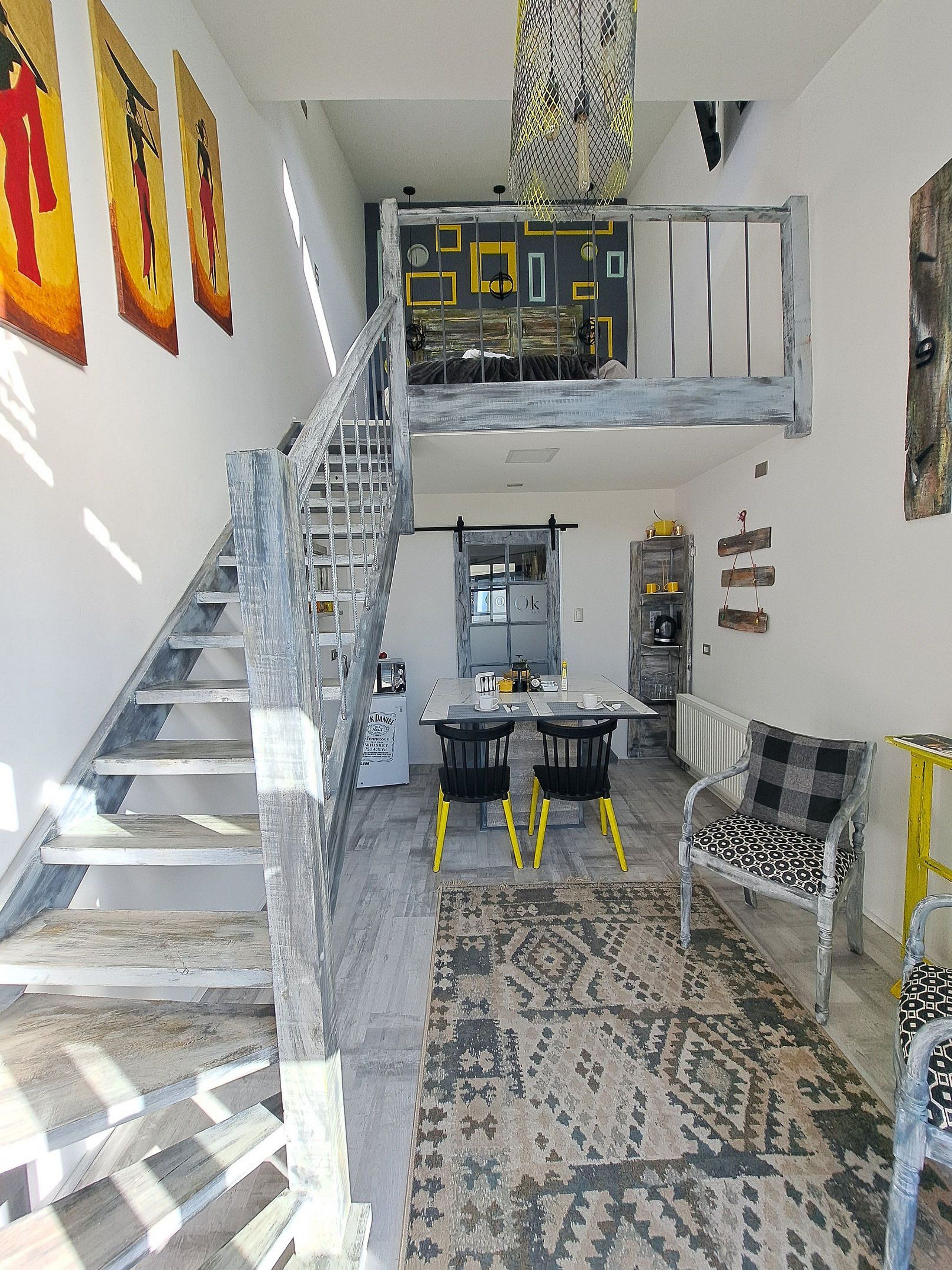 Ein Loft-Zimmer mit Treppe, Essbereich und einer Couch.