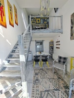 A loft-style room with a staircase, a dining area, and a sofa.