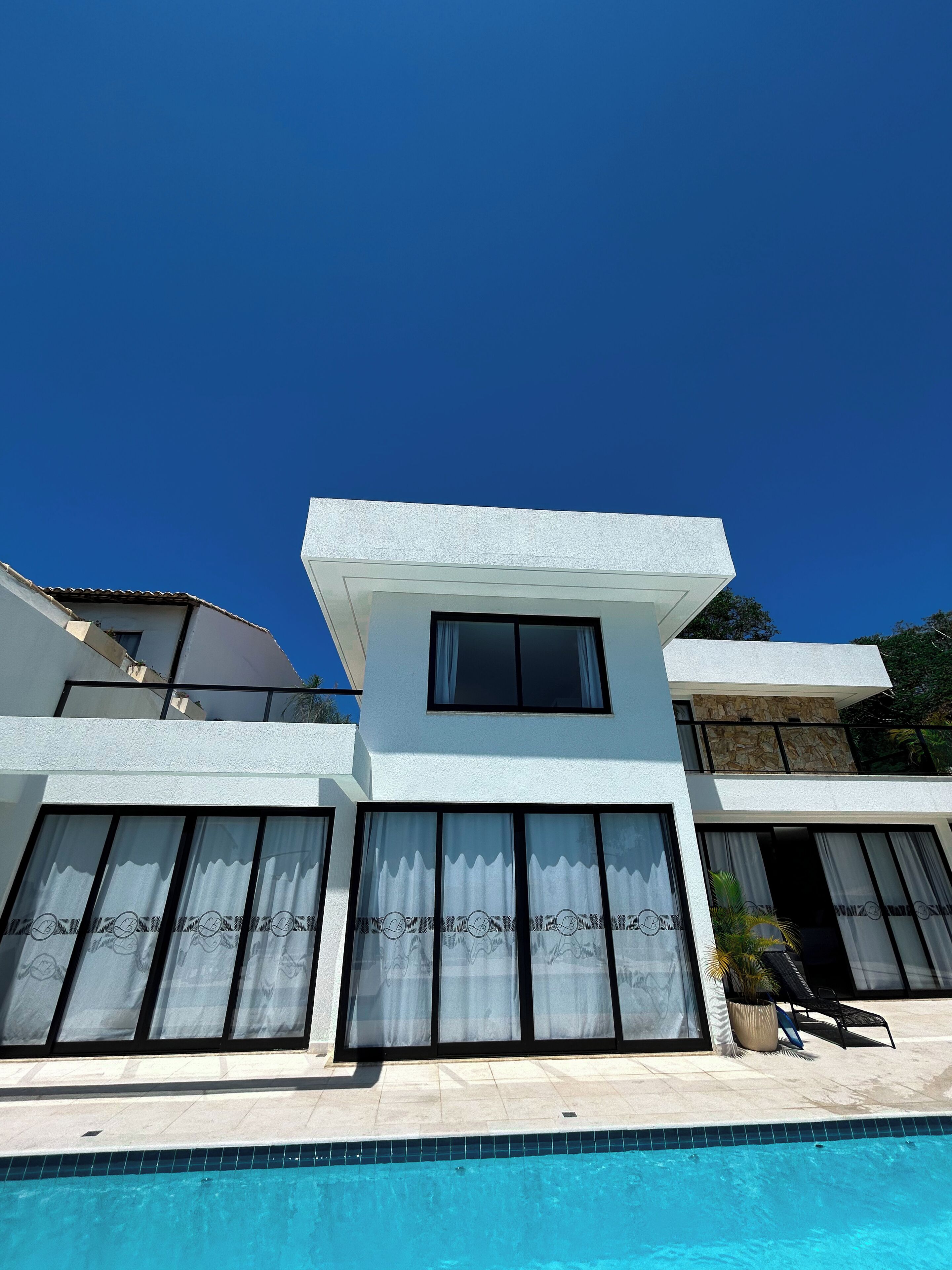 A modern two-story building with a swimming pool in front.