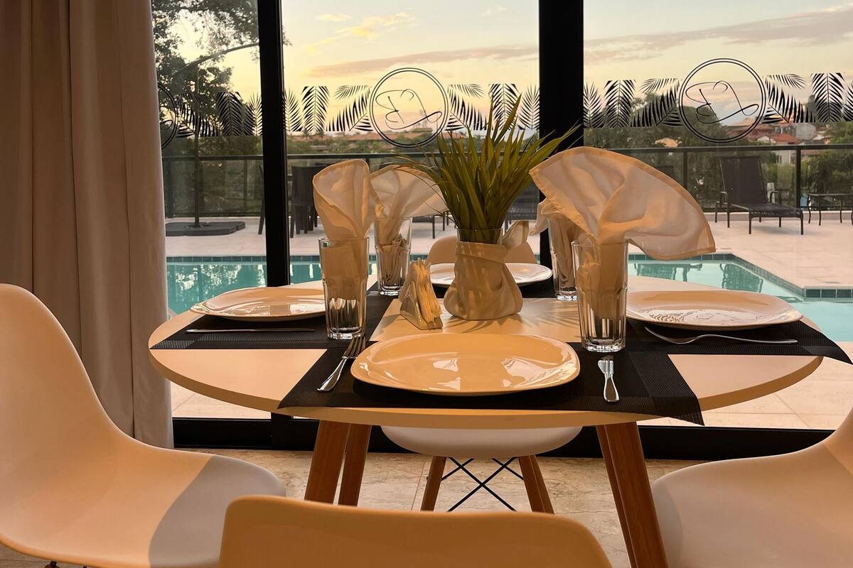 Mesa para dos personas con vistas a una piscina y árboles.
