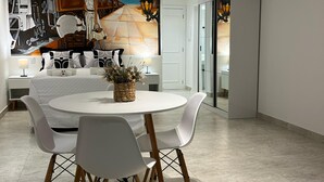A modern dining area with a round table, white chairs, and a mural on the wall.