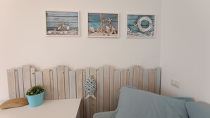 A room with a wooden headboard, a blue plant, and three framed artworks on the wall. - Le Terrazze - Three-room apartment with terrace and shared pool on Lake Iseo (Fonteno)