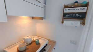 A kitchenette with a stove, a kettle, and a teapot. There is a sign on the wall that reads "La Maison du Café" and "Bistrot de Paris." - Le Terrazze - Three-room apartment with terrace and shared pool on Lake Iseo (Fonteno)