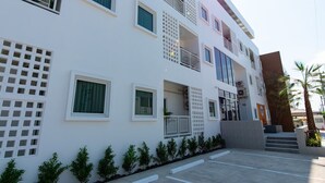 A multi-story building with balconies, a gated entrance, and a small garden area. - Matini Premium Hotel (Thanyaburi)