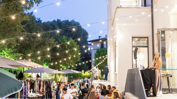 Un mercato all'aperto con luci a tendina, tende e persone.
