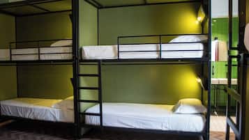 Een slaapkamer met stapelbedden, een houten visgraatvloer, groene wanden en een spiegel aan de rechterkant.