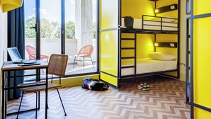 Una stanza con un letto a castello, una scrivania con un portatile e una sedia.
