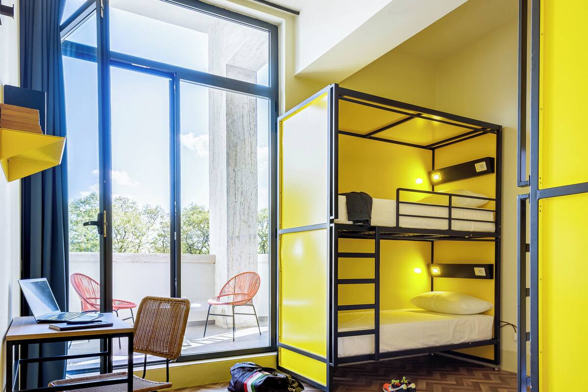 Une chambre avec un lit superposé, un bureau avec un ordinateur portable et une chaise.