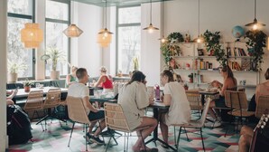 Un caffè moderno con ampie finestre, mobili in vimini e diverse piante.