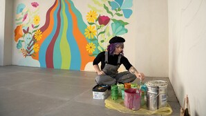 Una persona dipinge un murale colorato su una parete.