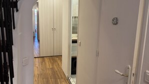 En smal hall med trägolv, vita väggar och en dörr med ett vitt handtag.