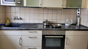 Eine Küche mit Mikrowelle, Herd, Backofen, Spüle und Schränken.