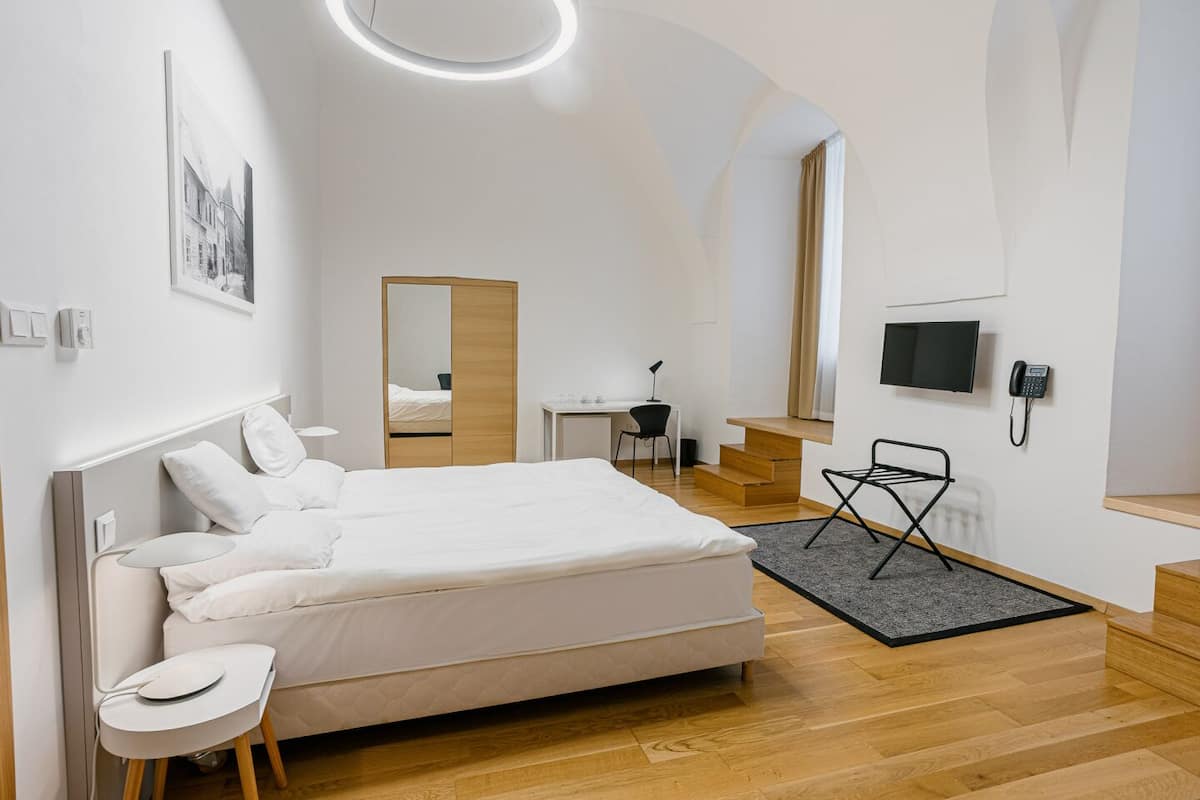 Un dormitorio moderno con una cama grande, un escritorio, una silla y un televisor.