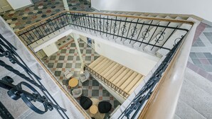 A multi-level interior with a staircase, checkered flooring, and a seating area with round tables and chairs. - Hotel Benedict (Koszeg)