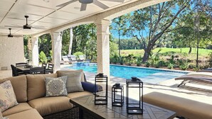 An outdoor patio area with a pool, seating, and a ceiling fan. - Luxury Palmetto Dunes Home w/ Private Pool (Hilton Head Island)