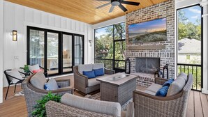 A covered patio with wicker furniture, a fireplace, and a ceiling fan. - Luxury Palmetto Dunes Home w/ Private Pool (Hilton Head Island)
