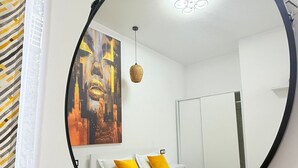 Ett sovrum med en säng, en spegel, en tavla och en hängande lampa.