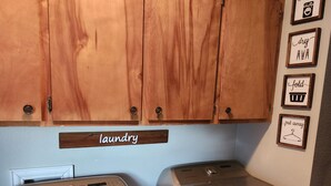 Un área de lavandería con armarios de madera y una lavadora y secadora Samsung.