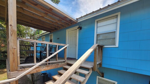 Una casa azul con una escalera de madera que lleva a un porche cubierto.
