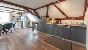 Een moderne keuken met grijze kastjes, een ingebouwde magnetron en een houten plafond.