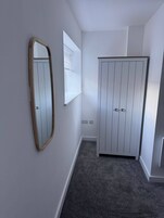 A hallway with a mirror, a window, and a wardrobe.