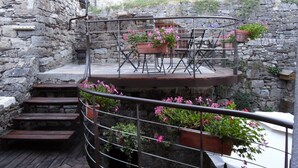 A spiral staircase with outdoor seating and potted plants. - Spacious apartment in cévenol village house (Barre-des-Cévennes)