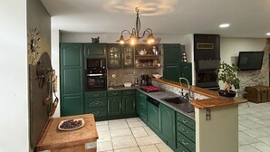 A kitchen with green cabinets, a wooden island, a built-in oven, and a stone backsplash. - Spacious apartment in cévenol village house (Barre-des-Cévennes)