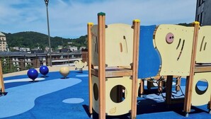 Un parque infantil con estructuras de juego coloridas y suelo azul.