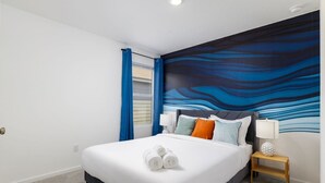 A modern hotel room with a large bed, a blue abstract mural on the wall, and a wooden nightstand with a lamp. - *NEW* The Boho Bungalow | 20%  Discount | BOOK NOW (New Braunfels)