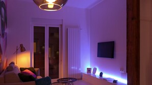 A living room with a sofa, a coffee table, a TV mounted on the wall, and a sliding glass door leading to a balcony. - Apartamento Kursal by SanSe Holidays (Donostia)