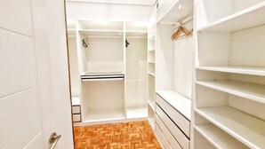 A walk-in closet with open shelves, a hanging rod, and a wooden parquet floor. - Apartamento Urbieta by SanSe Holidays (Donostia)