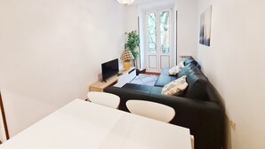 A modern living room with a sofa, a dining table, and a TV. - Apartamento Urbieta by SanSe Holidays (Donostia)