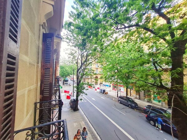 A street view with buildings, trees, and parked cars.