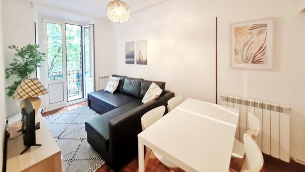 A modern living room with a black sofa, white table, and a large window. - Apartamento Urbieta by SanSe Holidays (Donostia)