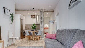 A modern living room with a grey sofa, a dining area with a wooden table and chairs, and a kitchen in the background. - Gran Vía Arena by SanSe Holidays (San Sebastián)