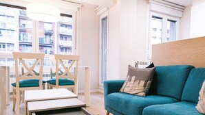 Un salon moderne avec un canapé de couleur turquoise, des chaises en bois et une petite table.